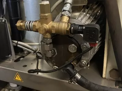 Internal view of a Nilfisk SH Truck Booster pump setup prior to installing an over-temperature protection system. The machine had previously suffered overheating issues due to continuous running caused by leaking trigger guns.